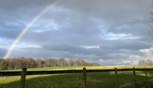 Landschaft mit Regenbogen über dem Hof
